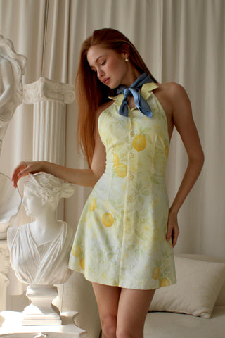 Woman wearing a butter yellow and pale blue floral citrus print linen mini dress in an elegant, light room